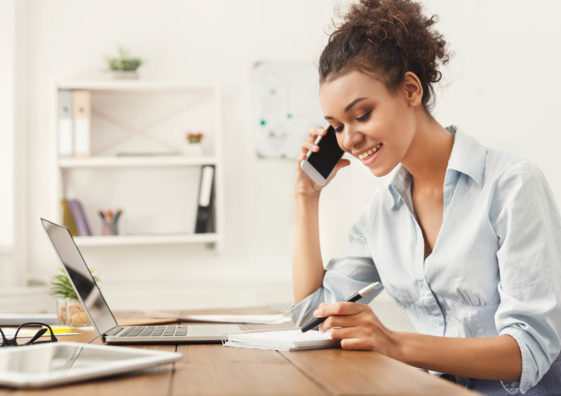 Smiling business woman at work talking on phone